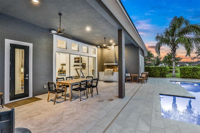 6294 W Fallsgrove Ln, Port Orange, FL 32128 - patio terrace at dusk featuring ceiling fan, exterior kitchen, a patio area, and outdoor dining space