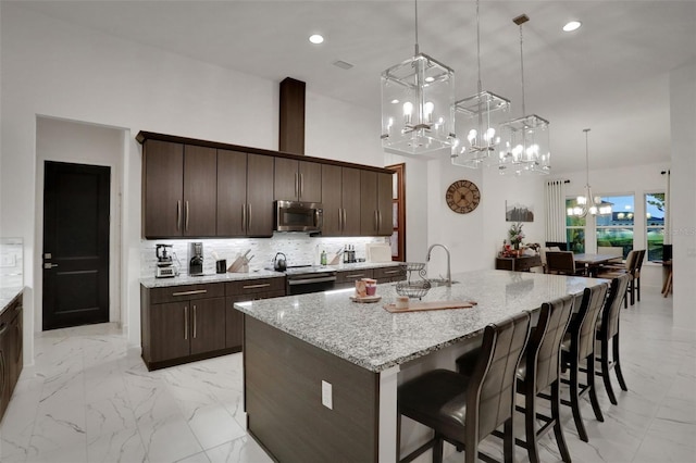 6294 W Fallsgrove Ln, Port Orange, FL 32128 - kitchen featuring stainless steel appliances, a chandelier, light marble finish flooring, tasteful backsplash, and a breakfast bar area