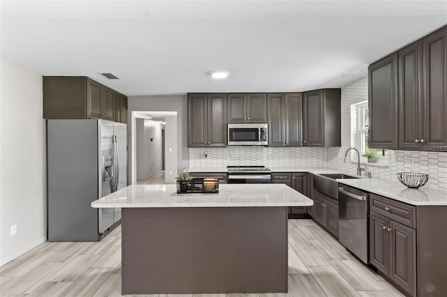 800 Black Duck Dr, Port Orange, FL 32127 - kitchen featuring appliances with stainless steel finishes, a kitchen island, tasteful backsplash, light stone countertops, and light wood-style flooring