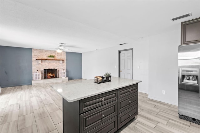 800 Black Duck Dr, Port Orange, FL 32127 - kitchen featuring stainless steel fridge, ceiling fan, a large fireplace, light stone counters, and wood finish floors
