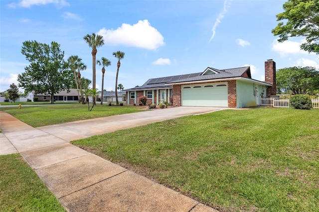 800 Black Duck Dr, Port Orange, FL 32127 - ranch-style house with roof mounted solar panels, concrete driveway, an attached garage, brick siding, and a chimney