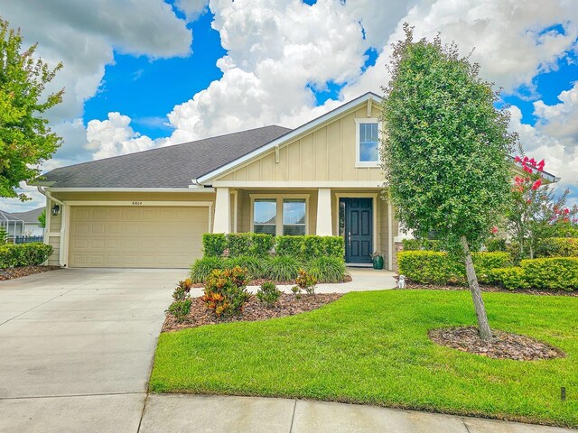 6804 Forkmead Ln, Port Orange, FL 32128 - view of front of property with board and batten siding, an attached garage, a front lawn, driveway, and a shingled roof