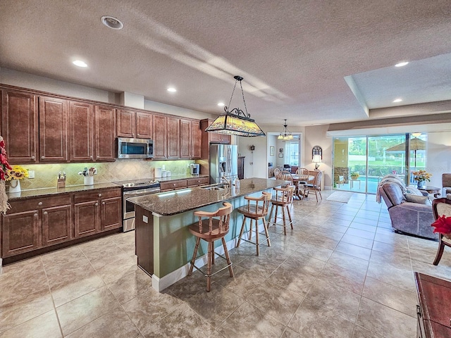 6804 Forkmead Ln, Port Orange, FL 32128 - kitchen with appliances with stainless steel finishes, a kitchen bar, an island with sink, a textured ceiling, and backsplash