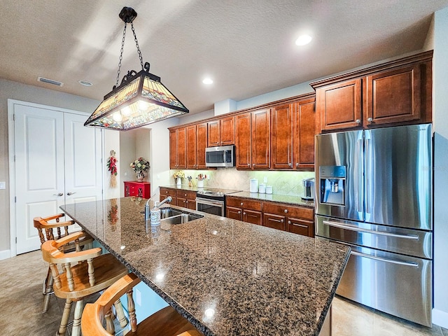 6804 Forkmead Ln, Port Orange, FL 32128 - kitchen with appliances with stainless steel finishes, a breakfast bar, a kitchen island with sink, dark stone countertops, and tasteful backsplash
