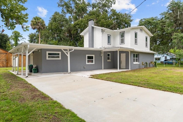 2005 Sunny Ln, New Smyrna Beach, FL 32168 - rear view of house featuring a chimney, a lawn, driveway, and an attached carport