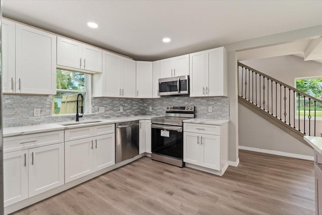 2005 Sunny Ln, New Smyrna Beach, FL 32168 - kitchen with appliances with stainless steel finishes, white cabinets, light wood-style flooring, backsplash, and recessed lighting