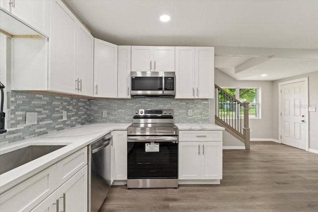 2005 Sunny Ln, New Smyrna Beach, FL 32168 - kitchen with stainless steel appliances, white cabinets, tasteful backsplash, light wood finished floors, and recessed lighting