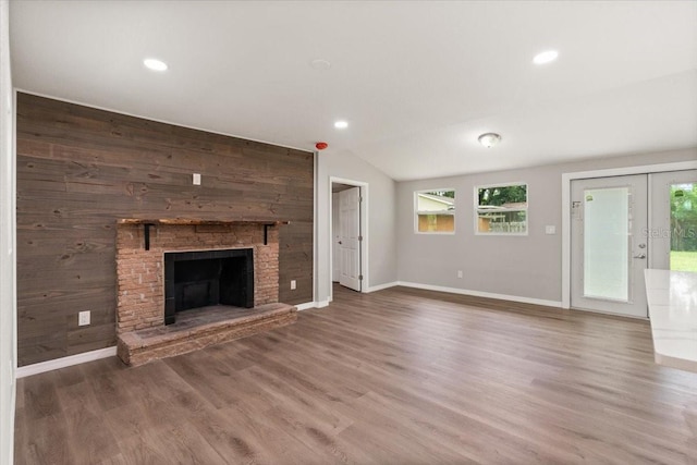 2005 Sunny Ln, New Smyrna Beach, FL 32168 - unfurnished living room featuring wood finished floors, a brick fireplace, french doors, recessed lighting, and lofted ceiling