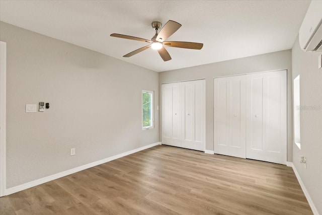 2005 Sunny Ln, New Smyrna Beach, FL 32168 - unfurnished bedroom featuring an AC wall unit, multiple closets, light wood-style floors, and ceiling fan