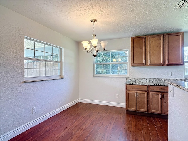 3045 Pine Tree Dr, Edgewater, FL 32141 - kitchen featuring dark wood-style flooring, a chandelier, a textured wall, brown cabinetry, and a textured ceiling