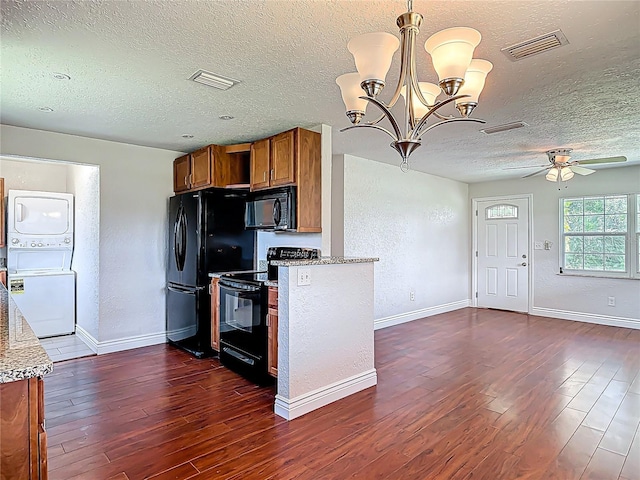 3045 Pine Tree Dr, Edgewater, FL 32141 - kitchen with brown cabinetry, black appliances, stacked washing machine and dryer, a textured ceiling, and dark wood-type flooring