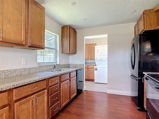 3045 Pine Tree Dr, Edgewater, FL 32141 - kitchen featuring stacked washer / drying machine, black appliances, a textured ceiling, dark wood-style floors, and brown cabinets