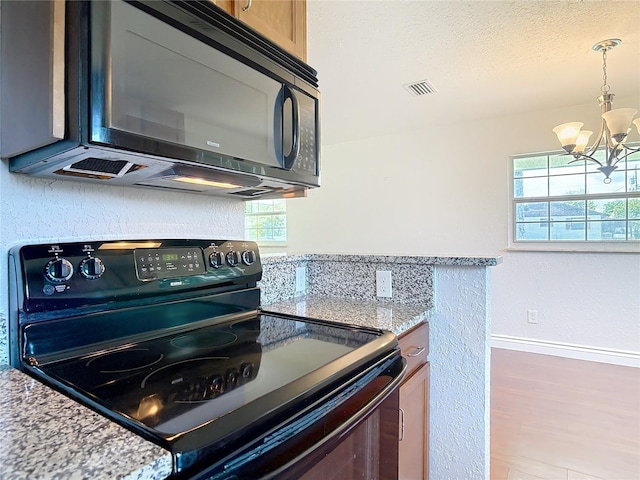 3045 Pine Tree Dr, Edgewater, FL 32141 - kitchen with black appliances, a chandelier, healthy amount of natural light, a textured ceiling, and light stone countertops