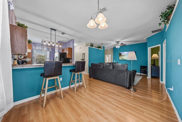 411 Ryans Ridge Ave, Eustis, FL 32726 - living room featuring light wood-type flooring, a textured ceiling, ceiling fan, and a chandelier
