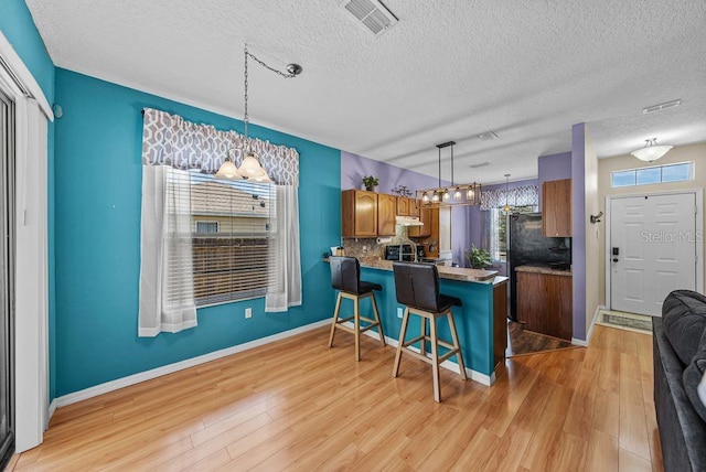 411 Ryans Ridge Ave, Eustis, FL 32726 - kitchen with brown cabinetry, a peninsula, tasteful backsplash, a textured ceiling, and a breakfast bar area