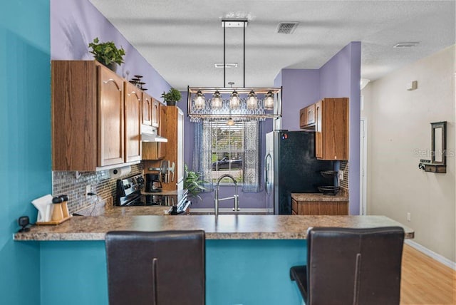 411 Ryans Ridge Ave, Eustis, FL 32726 - kitchen featuring under cabinet range hood, freestanding refrigerator, a peninsula, electric range oven, and decorative backsplash