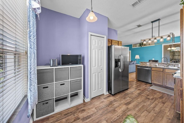 411 Ryans Ridge Ave, Eustis, FL 32726 - kitchen featuring stainless steel appliances, brown cabinets, dark wood-type flooring, hanging light fixtures, and light stone countertops