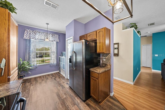 411 Ryans Ridge Ave, Eustis, FL 32726 - kitchen featuring stainless steel fridge with ice dispenser, a textured ceiling, brown cabinetry, wood finished floors, and pendant lighting