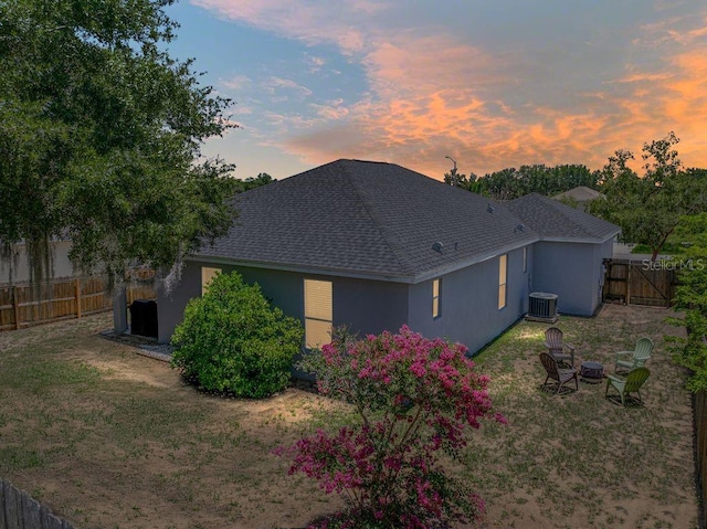 411 Ryans Ridge Ave, Eustis, FL 32726 - back of house at dusk with stucco siding, a shingled roof, a fenced backyard, and a fire pit