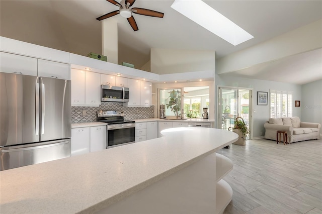 904 Clubhouse Blvd, New Smyrna Beach, FL 32168 - kitchen with stainless steel appliances, a skylight, light countertops, white cabinetry, and open floor plan