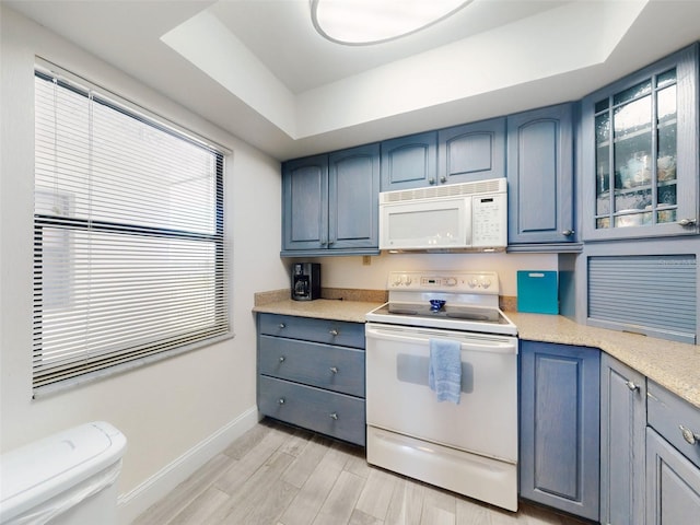 4175 S Atlantic Ave Unit 4110, New Smyrna Beach, FL 32169 - kitchen with white appliances, a tray ceiling, blue cabinetry, light countertops, and light wood-style flooring