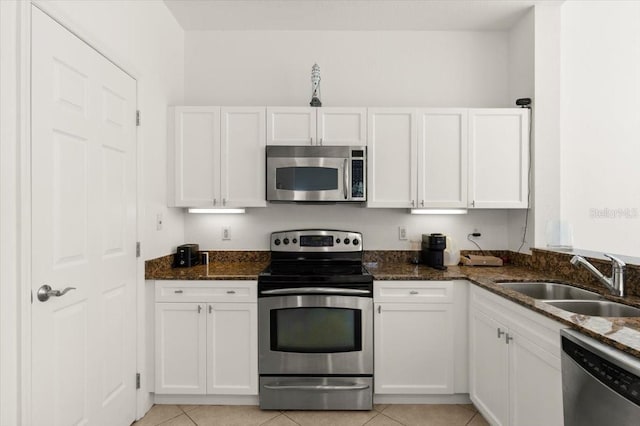 2 Oceans W Blvd Unit 206, Daytona Beach Shores, FL 32118 - kitchen featuring stainless steel appliances, white cabinetry, dark stone counters, and light tile patterned floors