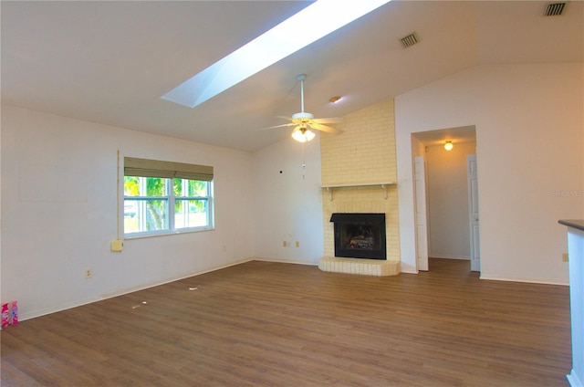 2548 Crestwood Ave, New Smyrna Beach, FL 32168 - unfurnished living room featuring vaulted ceiling, wood finished floors, ceiling fan, a brick fireplace, and a skylight