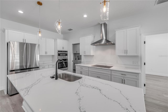 2324 Orange Tree Dr, Edgewater, FL 32141 - kitchen with wall chimney exhaust hood, appliances with stainless steel finishes, light wood-type flooring, white cabinetry, and hanging light fixtures