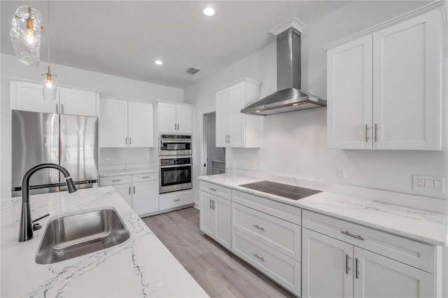 2324 Orange Tree Dr, Edgewater, FL 32141 - kitchen with stainless steel appliances, wall chimney range hood, white cabinetry, light wood-style flooring, and recessed lighting