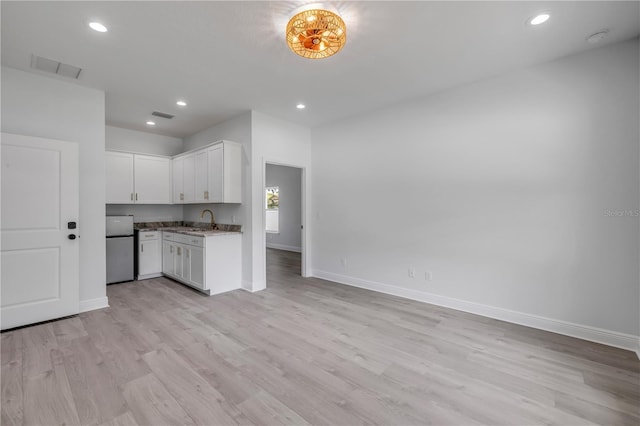2324 Orange Tree Dr, Edgewater, FL 32141 - kitchen with freestanding refrigerator, light wood finished floors, white cabinets, recessed lighting, and open floor plan