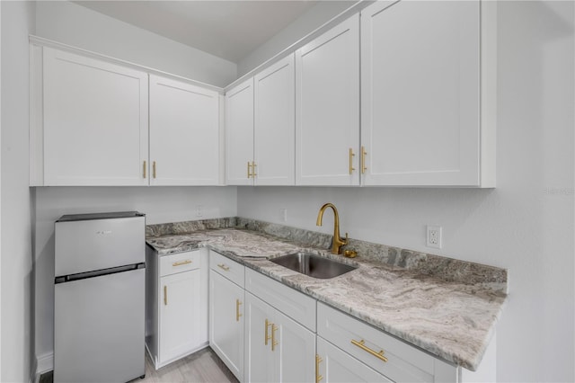 2324 Orange Tree Dr, Edgewater, FL 32141 - kitchen featuring freestanding refrigerator, white cabinetry, light stone counters, and light wood-style floors