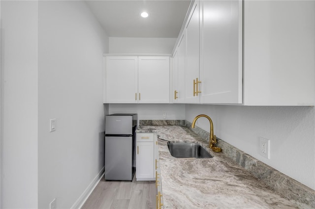 2324 Orange Tree Dr, Edgewater, FL 32141 - kitchen with freestanding refrigerator, light stone countertops, white cabinetry, light wood-style flooring, and recessed lighting