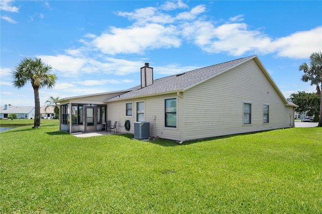684 Rochester Ct, New Smyrna Beach, FL 32168 - back of property with a sunroom, a chimney, a lawn, and a shingled roof