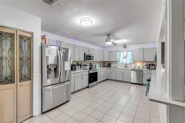 2715 Pine Tree Dr, Edgewater, FL 32141 - kitchen featuring stainless steel appliances, light countertops, backsplash, ceiling fan, and light tile patterned floors