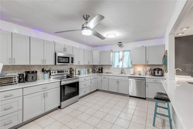 2715 Pine Tree Dr, Edgewater, FL 32141 - kitchen with stainless steel appliances, backsplash, light countertops, a ceiling fan, and gray cabinets