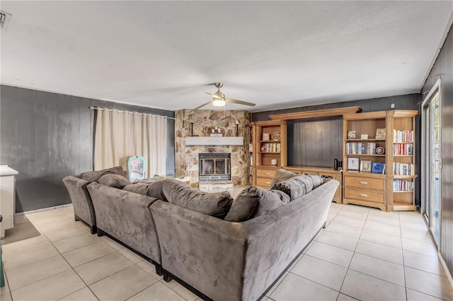 2715 Pine Tree Dr, Edgewater, FL 32141 - living area featuring light tile patterned floors, a ceiling fan, wood walls, and a fireplace
