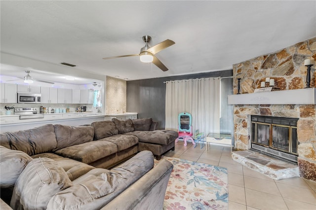 2715 Pine Tree Dr, Edgewater, FL 32141 - living room featuring ceiling fan, light tile patterned flooring, and a stone fireplace