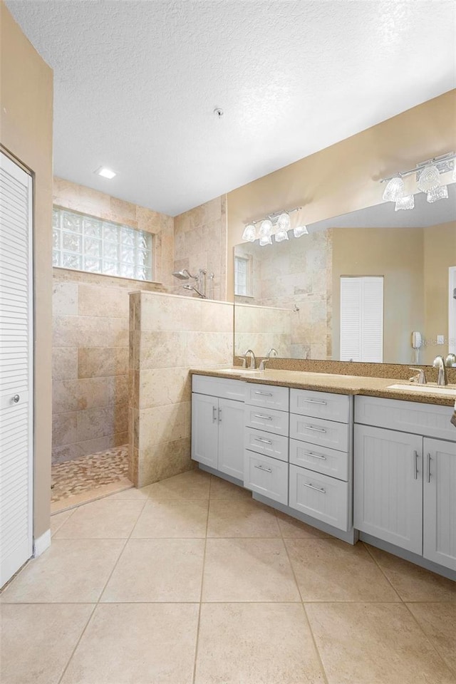 438 Bouchelle Dr Unit 105, New Smyrna Beach, FL 32169 - bathroom featuring a walk in shower, double vanity, a textured ceiling, tile patterned floors, and tile walls