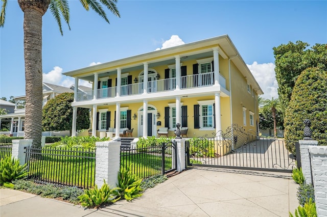 1212 S Riverside Dr, New Smyrna Beach, FL 32168 - neoclassical home with covered porch, a balcony, a gate, and a fenced front yard