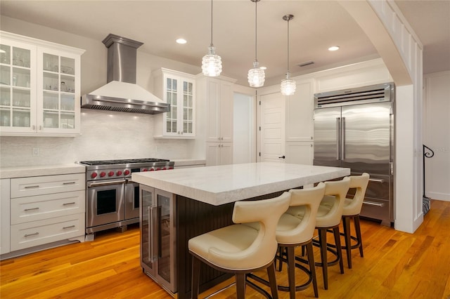 1212 S Riverside Dr, New Smyrna Beach, FL 32168 - kitchen with wall chimney exhaust hood, premium appliances, a kitchen island, wine cooler, and white cabinetry