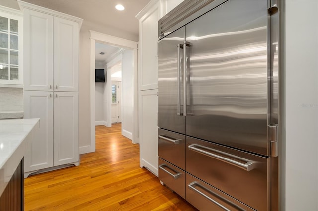 1212 S Riverside Dr, New Smyrna Beach, FL 32168 - kitchen featuring stainless steel built in refrigerator, white cabinets, light wood-style floors, glass insert cabinets, and recessed lighting