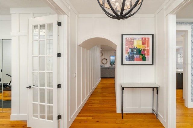1212 S Riverside Dr, New Smyrna Beach, FL 32168 - corridor with a decorative wall, arched walkways, light wood-style flooring, and a chandelier
