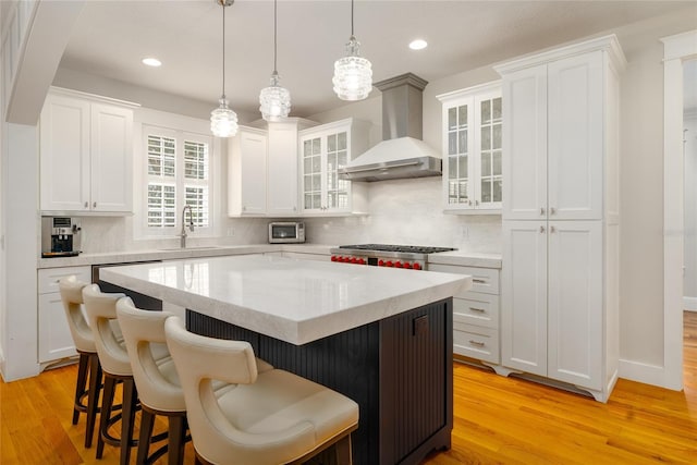 1212 S Riverside Dr, New Smyrna Beach, FL 32168 - kitchen with wall chimney exhaust hood, a kitchen breakfast bar, a kitchen island, white cabinetry, and recessed lighting