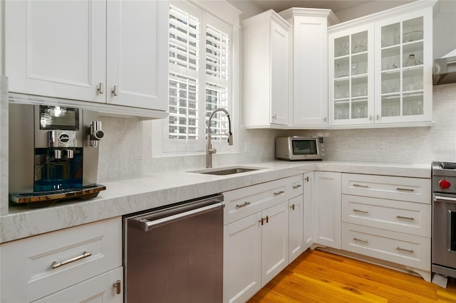 1212 S Riverside Dr, New Smyrna Beach, FL 32168 - kitchen featuring appliances with stainless steel finishes, light countertops, white cabinetry, tasteful backsplash, and glass insert cabinets