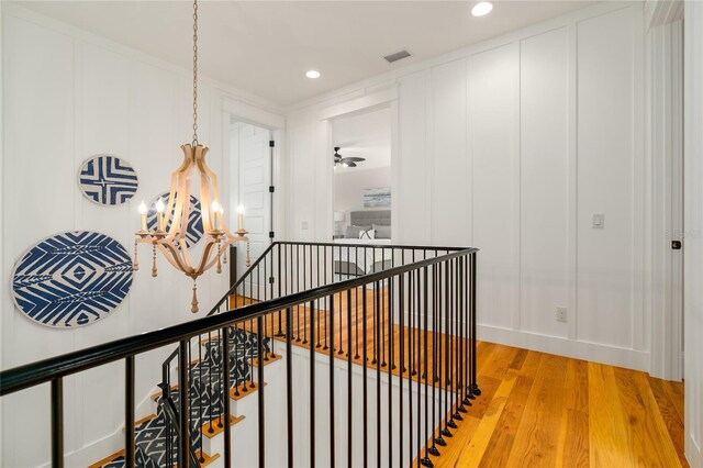 1212 S Riverside Dr, New Smyrna Beach, FL 32168 - hallway with a chandelier, an upstairs landing, light wood-style flooring, recessed lighting, and a decorative wall