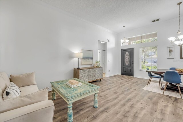 5849 Ansley Way, Mount Dora, FL 32757 - living area featuring a chandelier, ornamental molding, wood finished floors, a textured ceiling, and a high ceiling