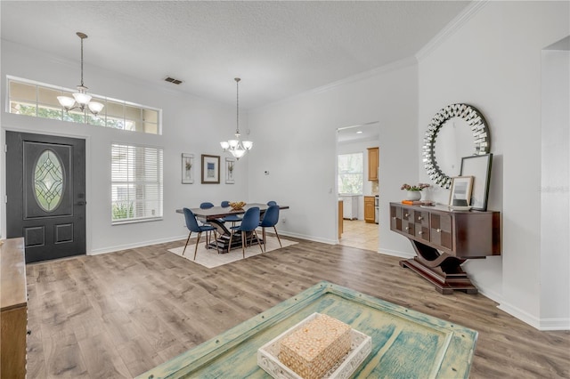 5849 Ansley Way, Mount Dora, FL 32757 - foyer entrance with a chandelier, light wood-type flooring, crown molding, and a textured ceiling