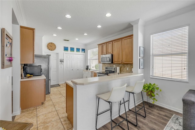 5849 Ansley Way, Mount Dora, FL 32757 - kitchen with appliances with stainless steel finishes, decorative backsplash, a kitchen bar, recessed lighting, and crown molding