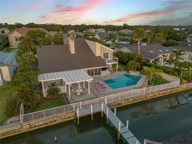 1219 Commodore Dr, New Smyrna Beach, FL 32168 - back of house at dusk with a fenced backyard, a balcony, a residential view, and a water view