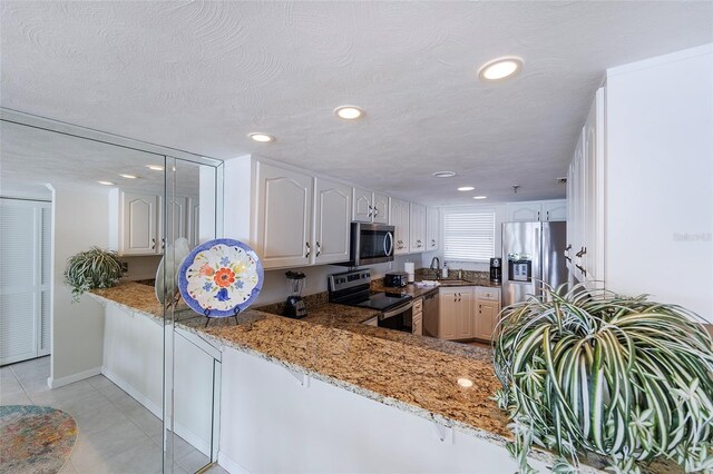 1051 Ocean Shore Blvd Unit 502, Ormond Beach, FL 32176 - kitchen with appliances with stainless steel finishes, light stone counters, light tile patterned floors, a peninsula, and recessed lighting